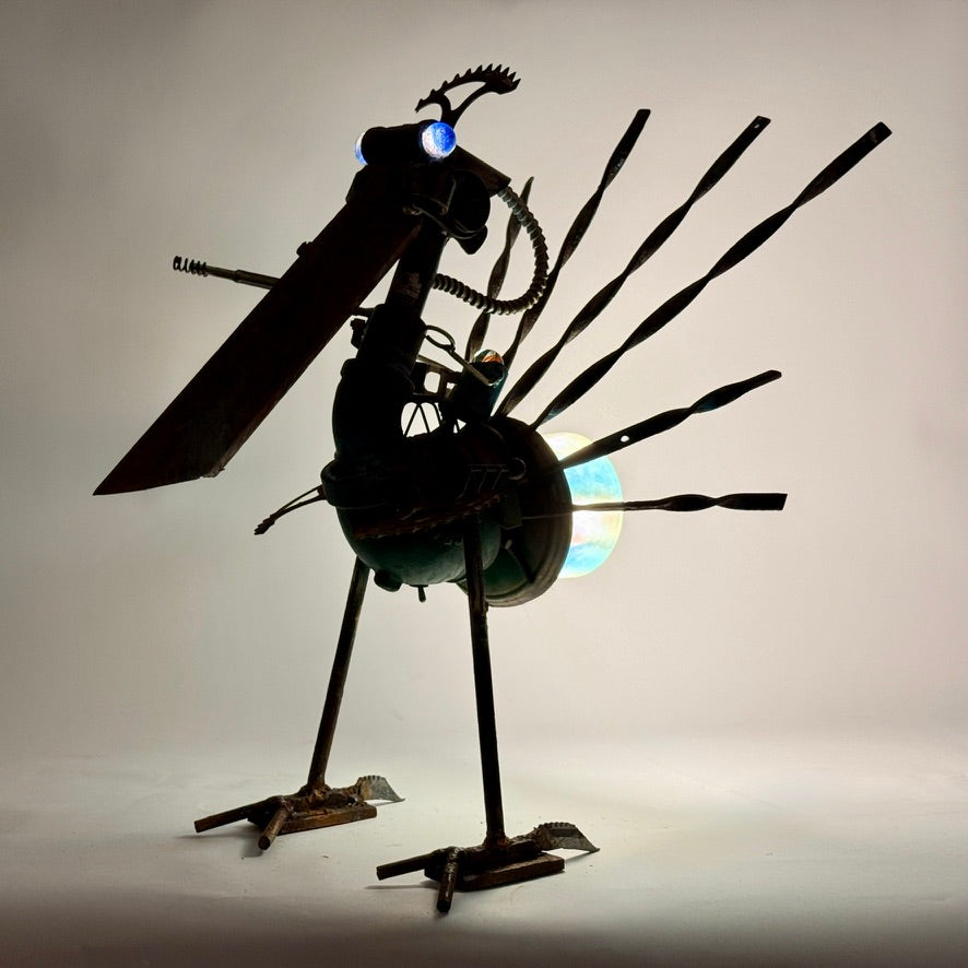 Battle Bird reclaimed metal bird sculpture with sprocket feathers and alien sniper bot rider, backlight