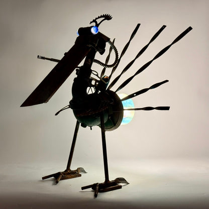 Battle Bird reclaimed metal bird sculpture with sprocket feathers and alien sniper bot rider, backlight