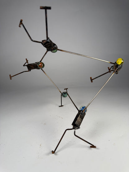 We Got This original reclaimed metal sculpture by Bobby Anderson featuring five interconnected figures with glass marble heads